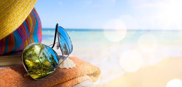 Sonnenbrille, Handtuch und Hut am Strand